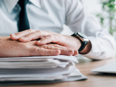 Insurance agent with stack of policy contracts on office desk
